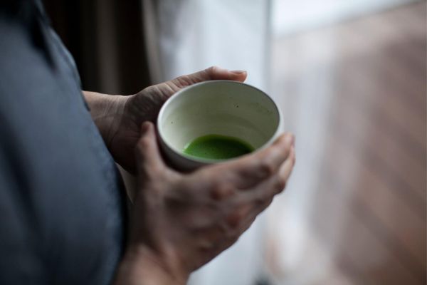 Holding cup of matcha green tea