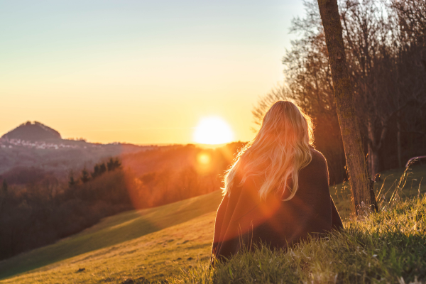 Woman sitting on grass gazing peacefully at the sunset